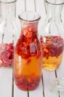 Vista close-up de morangos e vinagre em garrafas de preservação — Fotografia de Stock