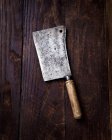 Closeup top view of an antique meat cleaver on a wooden surface — Stock Photo