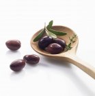 Черные оливки с деревянной ложкой — стоковое фото