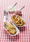Nahaufnahme von gebratenem Huhn mit Chips, Ketchup und Remoulade auf einer karierten Tischdecke — Stockfoto