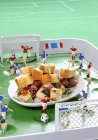 Vista elevada de nuggets de pollo con tocino y salvia con decoraciones de fútbol - foto de stock