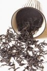 Folhas de chá derramando fora de uma xícara — Fotografia de Stock