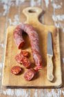 Elevated view of sliced Chorizo on wooden board with a knife — Stock Photo