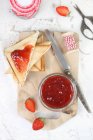 Top view of homemade strawberry jam in a jar and on triangles of toast — Stock Photo