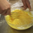 Closeup view of hands beating egg yolk with a whisk — Stock Photo