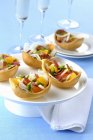 Pastry shells filled with Prosciutto, grapefruit and vegetables on white plate over blue surface — Stock Photo