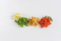 Draufsicht auf drei Arten von Tobiko-Fischrogen mit Zitronenscheiben und Dill auf weißer Oberfläche — Stockfoto