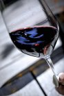 Verre de vin rouge tenu à angle — Photo de stock