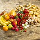 Un arreglo de verduras, setas y frutas en una mesa de madera - foto de stock