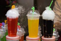 Closeup view of colored soft drinks in plastic cups on a market stand — Stock Photo