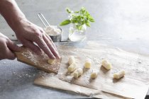 Cropped view of person rolling Gnocchi on a board — Stock Photo