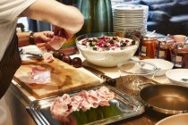 Cropped view of person arranging ham on a platter — Stock Photo