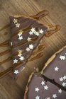 Nahaufnahme von oben: Tarte au Chocolat mit kleinen weißen Sternen und Karamellsoße auf einem Holzbrett — Stockfoto