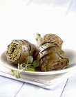 Carciofi alla romana - artichokes with fresh herbs on white plate over towel — Stock Photo