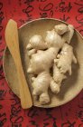 Fresh ginger roots on wooden plate — Stock Photo