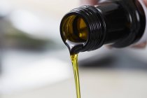 Vista close-up de derramar óleo de linho de uma garrafa — Fotografia de Stock