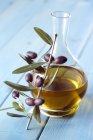 Carafe of olive oil and sprig of olives — Stock Photo