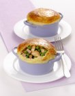 Mini chicken pies in blue pots over plates with fork — Stock Photo