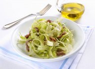 Puntarelle with anchovies on white plate over towel — Stock Photo