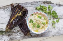 Baba ganoush with aubergine skins and coriander over wooden surface — Stock Photo