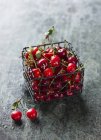 Cherries in small wire basket — Stock Photo