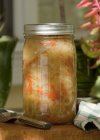 Homemade sauerkraut in a preserving jar over wooden surface — Stock Photo