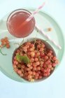 Closeup top view of fresh red currants and pink lemonade on blue plate — Stock Photo