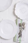 Вид зверху на три різні білі тарілки та срібні столові прибори на тканинній серветці — стокове фото