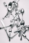 Vista dall'alto di varie forchette, coltelli e cucchiai su una superficie bianca — Foto stock