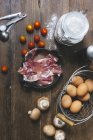 An arrangement of ingredients for tomato quiche with ham and mushrooms over wooden surface — Stock Photo
