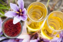 Closeup top view of an arrangement of saffron threads, saffron flowers and dissolved saffron in glasses — Stock Photo