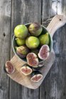 Figues fraîches avec tranches dans un bol — Photo de stock