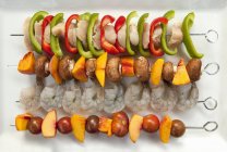 Assorted skewers for the barbecue on white platter — Stock Photo