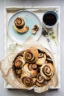 Top  view of sweet yeast swirls with a brown sugar, cinnamon and pecan nut filling on a tray with coffee — Stock Photo