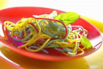 Espaguetis coloridos con albahaca - foto de stock