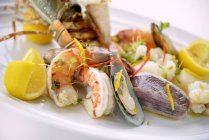 Vista close-up de prato de frutos do mar misturados com amêijoas, camarões e limão — Fotografia de Stock