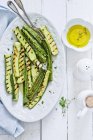 Grilled courgette and olive oil on white plate  over wooden surface — Stock Photo