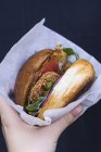 Mão segurando takeaway hambúrguer — Fotografia de Stock