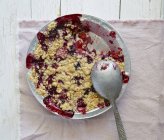 Closeup top view of berry crumble in bowl with spoon — Stock Photo