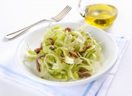Puntarelle con le acciughe puntarelle with anchovies on white plate over towel with fork — Stock Photo