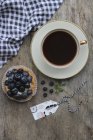 Gros plan vue de dessus de tasse de café et une tartelette aux myrtilles — Photo de stock