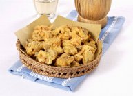 Closeup view of Frittelle di cozze with papers in wicker bowl on cloth — Stock Photo