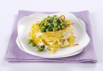 Baked spaghetti nest with cheese and peas — Stock Photo