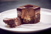 Close-up vista de corte de chocolate Petit quatro bolo com garfo na placa — Fotografia de Stock