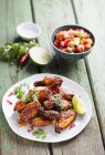 Chicken wings with avocado salsa on white plate  over wooden surface — Stock Photo