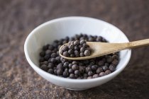 Closeup view of allspice with a wooden spoon in a bowl — Stock Photo