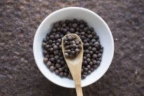 Closeup top view of allspice with a wooden spoon in a bowl — Stock Photo