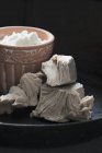 Closeup view of baking yeast in front of a clay pot with cream — Stock Photo