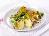Courgette gratinée fleurs remplies d'œufs sur assiette blanche — Photo de stock
