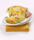 Italienische Kartoffelflan mit Mortadella auf weißem Teller über Handtuch — Stockfoto